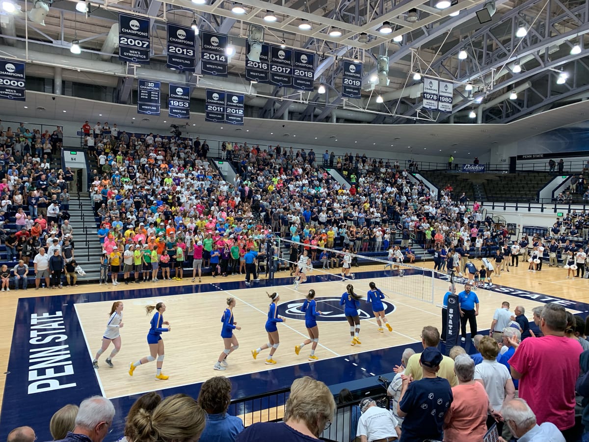 A 2019 photo inside the Rec Hall volleyball arena at Penn State, showing a sold out crowd and players warming up on the court before first serve
