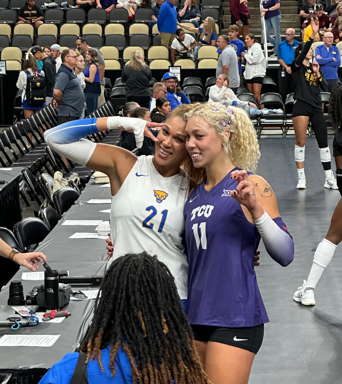 Post-match photo on the floor of PPG Paints Arena shows Bre Kelley posing with younger sister Becca, each in their volleyball uniforms