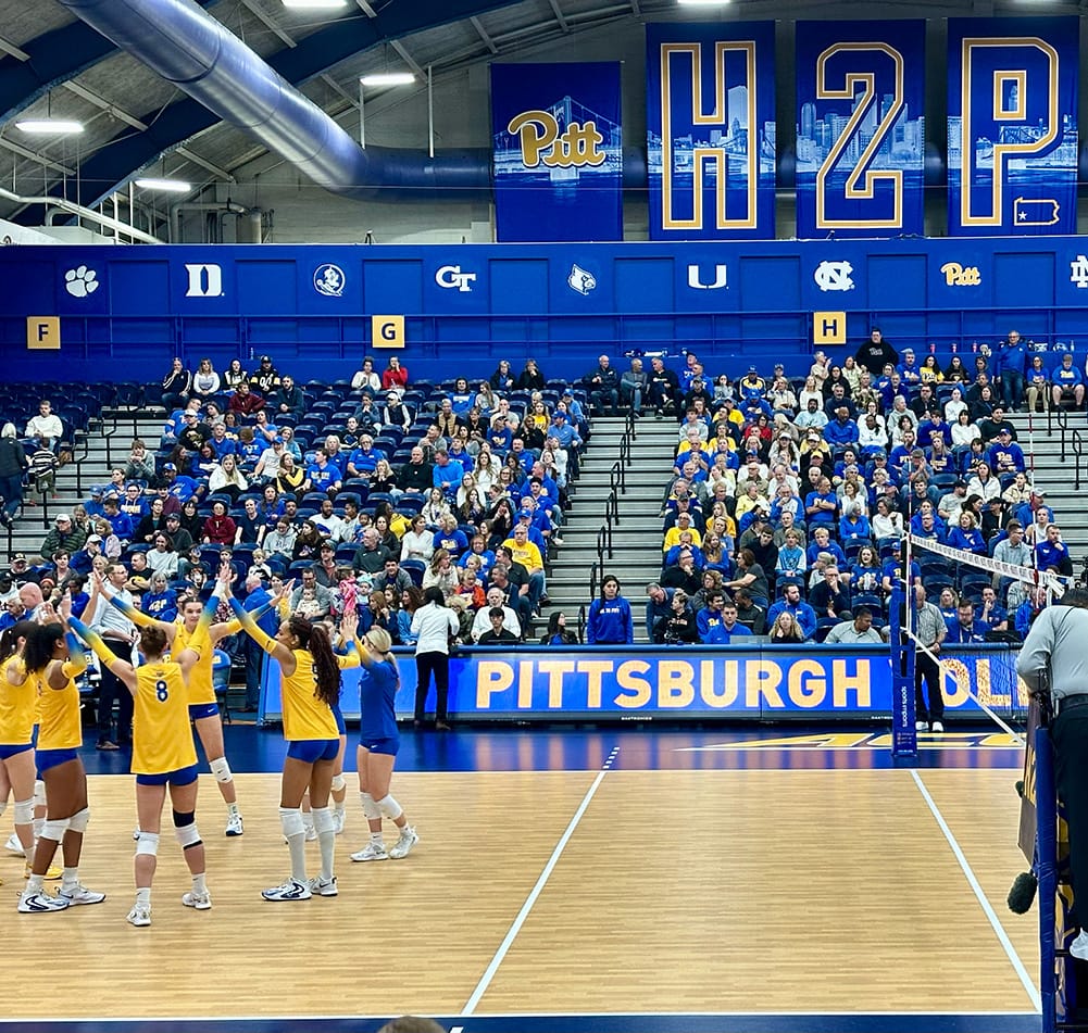 The Pitt Volleyball team in a circle on the court at Fitzgerald Fieldhouse with the Wake Forest volleyball team