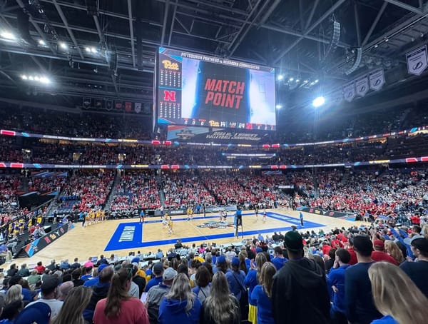 A view from the seating bowl of Amalie Arena in Tampa during match point of the 2023 Women's Volleyball Final Four. There are many fans looked toward a volleyball court.